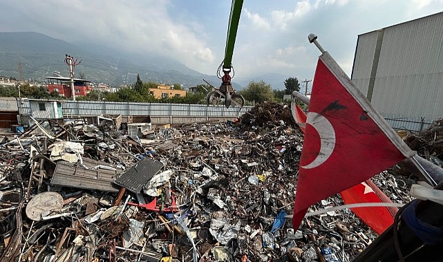 Hurda yığını içerisindeki Türk bayrağını elleriyle çıkararak iş makinesine astı