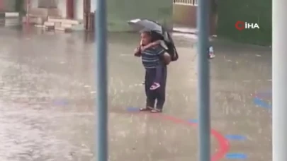Dede torununu sırtına alarak yağmur altında İstiklal Marşı okudu